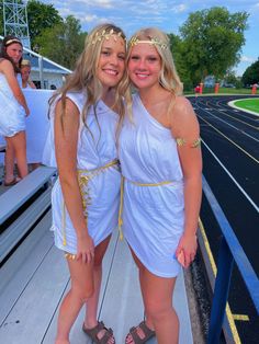 two women in white dresses standing next to each other on a stadium bleachers