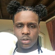 a man with black hair has two buns on his head and is wearing a white t - shirt