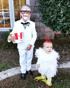 two children dressed in costumes standing next to each other on the grass and one is holding a cup