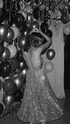 black and white photograph of woman in sequin dress with balloons hanging from the ceiling