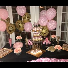 a table topped with lots of pink and gold desserts, cupcakes and cake