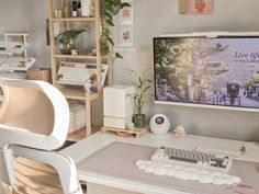 a desk with a computer, keyboard and plant in front of the monitor on it