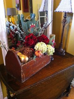 a wooden box filled with flowers on top of a table next to a lamp and mirror