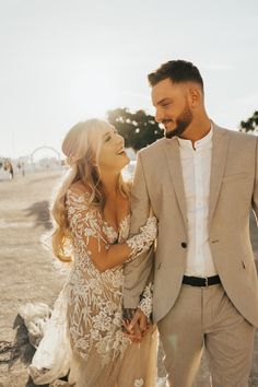 a man and woman are walking together in the desert holding hands while smiling at each other