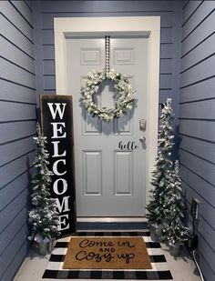 a welcome mat is on the front door with christmas trees and wreaths around it