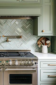 a stove top oven sitting inside of a kitchen next to green cupboards and drawers