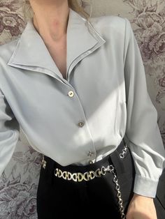 This vintage light gray blouse features a sleek, satin-like finish that gives it a refined and polished look. The blouse has a wide, structured collar and long sleeves, with minimal yet elegant buttons down the front. Its minimalist design exudes sophistication, making it a versatile piece perfect for both formal and casual outfits. The soft sheen adds a luxurious touch, making this blouse a timeless wardrobe essential. - Good vintage condition  - TAG SIZE: 42, F 44, US 14, GB 16, I 48 - Fabric Elegant Office Wear Shirt With Collared Neckline, Elegant Formal Shirt With Collared Neckline, Chic Party Blouse With Spread Collar, Chic Formal Shirt With Collared Neckline, Chic Spread Collar Blouse For Evening, Elegant Satin Office Shirt, Elegant Satin Shirt For Office, Chic Evening Blouse With Spread Collar, Chic Party Shirt With Spread Collar