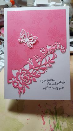 a pink and white greeting card with a butterfly on the front, sitting on a table