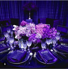 the table is set with purple flowers and silverware