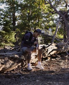 a man sitting on a log in the woods