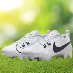 a pair of white and black nike soccer cleats on green grass with blurry background