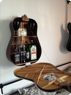 a guitar case sitting on top of a bed next to a wall mounted shelf filled with bottles