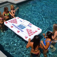 four girls in the pool playing with an inflatable game board and cups on it