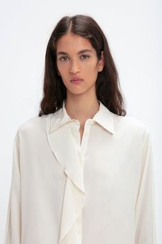 A single asymmetric drape detail cascades down the front of this silk blouse for a fluid silhouette that is enhanced by voluminous sleeves finished with buttoned cuffs. A concealed button-front closure maintains the elegant aesthetic, while the milky shade of Ivory has a nostalgic, romantic appeal. Styled with the Reverse Front Trouser Victoria Beckham Asymmetric Ruffle Blouse In Ivory  - Size 8 UK Elegant Asymmetrical Top With Ruffles, Elegant Asymmetrical Ruffled Tops, Chic Blouse With Draped Sleeves For Work, Elegant Long Sleeve Blouse With Draped Sleeves, Formal Long Sleeve Blouse With Draped Sleeves, Elegant Formal Tops With Draped Sleeves, Formal Blouse With Draped Long Sleeves, Elegant Asymmetrical Blouse With Draped Sleeves, Elegant Asymmetrical Formal Blouse