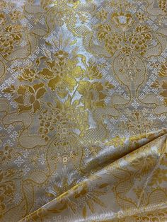 an image of a gold and silver fabric with floral designs on the side, as well as flowers