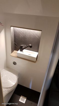 there is a small bathroom with a toilet and sink in the corner on the wall