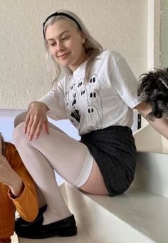 a woman sitting on top of a white step next to a small black and white dog