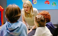 a woman talking to children in a classroom