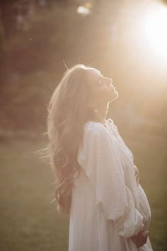 a woman is standing in the sun with her hair blowing back and looking up at something