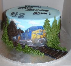 a birthday cake decorated with a train and trees