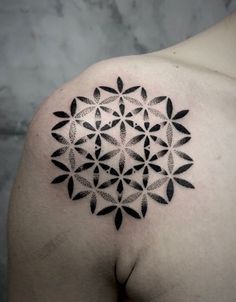 the back of a man's shoulder with an intricate tattoo design on his chest