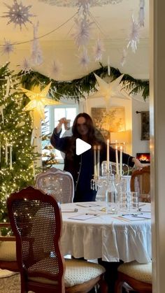 a woman standing in front of a christmas tree with candles on it and decorations hanging from the ceiling