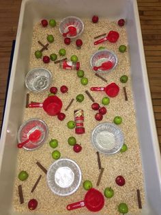 a white tray filled with bowls and spoons on top of a wooden table covered in sand