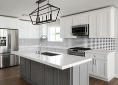 a large kitchen with white cabinets and stainless steel appliances, including an island in the middle