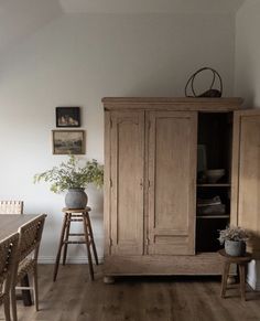 a wooden cabinet sitting in the corner of a room next to a table and chairs