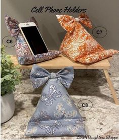 the cell phone holder is sitting on a table with two pillows and a bow tie