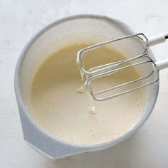 a white bowl filled with liquid and whisk attachments on top of it