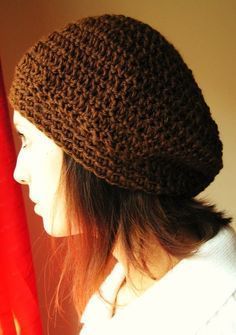 a woman wearing a brown crocheted beanie standing next to a red curtain