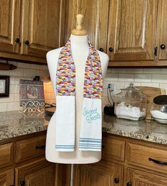 a woman's white scarf on top of a mannequin in a kitchen