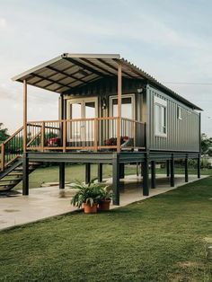 a small house on stilts in the middle of a grassy area with stairs leading up to it