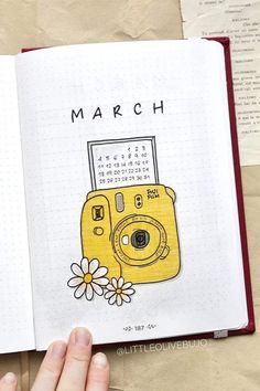 a hand is holding an open book with a camera on it and the words march written in