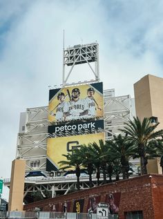 a large sign on the side of a building that says petco park in front of palm trees