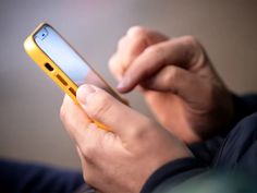 a close up of a person holding a cell phone in their hands and looking at the screen