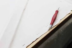 a red and white pen laying on top of a piece of paper with holes in it