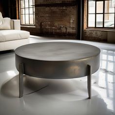 a white couch sitting next to a table on top of a hard wood floor in an empty room