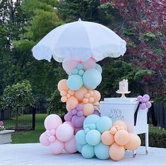 a bunch of balloons that are sitting on top of a table with an umbrella over it