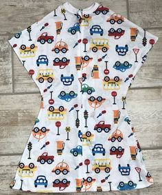 a child's shirt with cars and trucks on it, sitting on a wooden floor