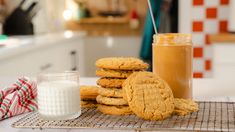 cookies and milk on a cooling rack in a kitchen with a glass of orange juice