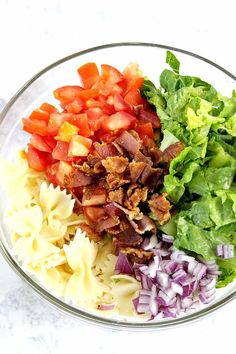 a bowl filled with pasta, lettuce, tomatoes and other toppings on top of it