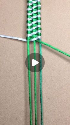 a video demonstrating how to tie the ends of two strands of green and white yarn