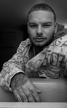 a black and white photo of a man with tattoos