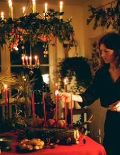 a woman standing in front of a table with candles on it and plates full of food