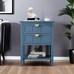 a blue table with two drawers and a white busturine in the corner next to it