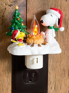 a light switch cover with a snoopy christmas scene on it and a charlie brown fire