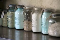 there are many jars lined up on the shelf in this room, each containing different kinds of grains