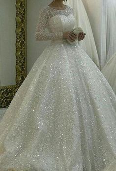 a woman in a white wedding dress standing next to a mirror